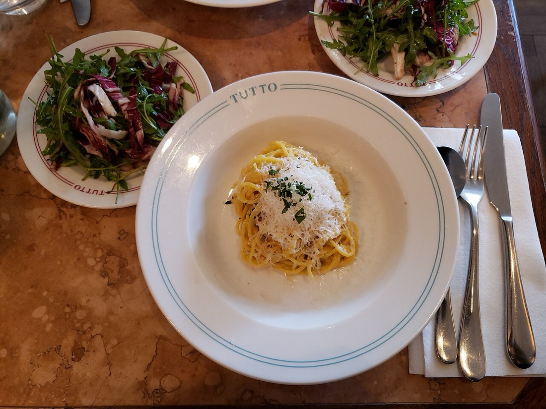 A plate of spaghetti with a side salad