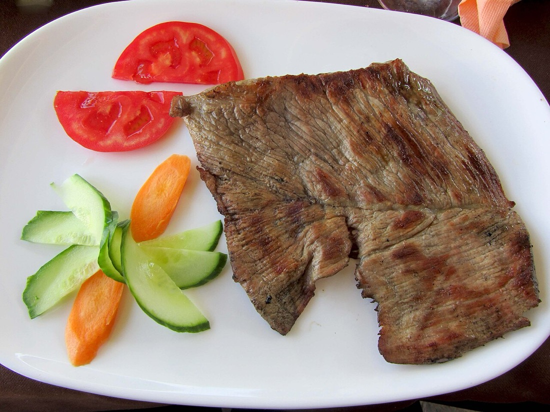 A beef steak cooked on a charcoal grill
