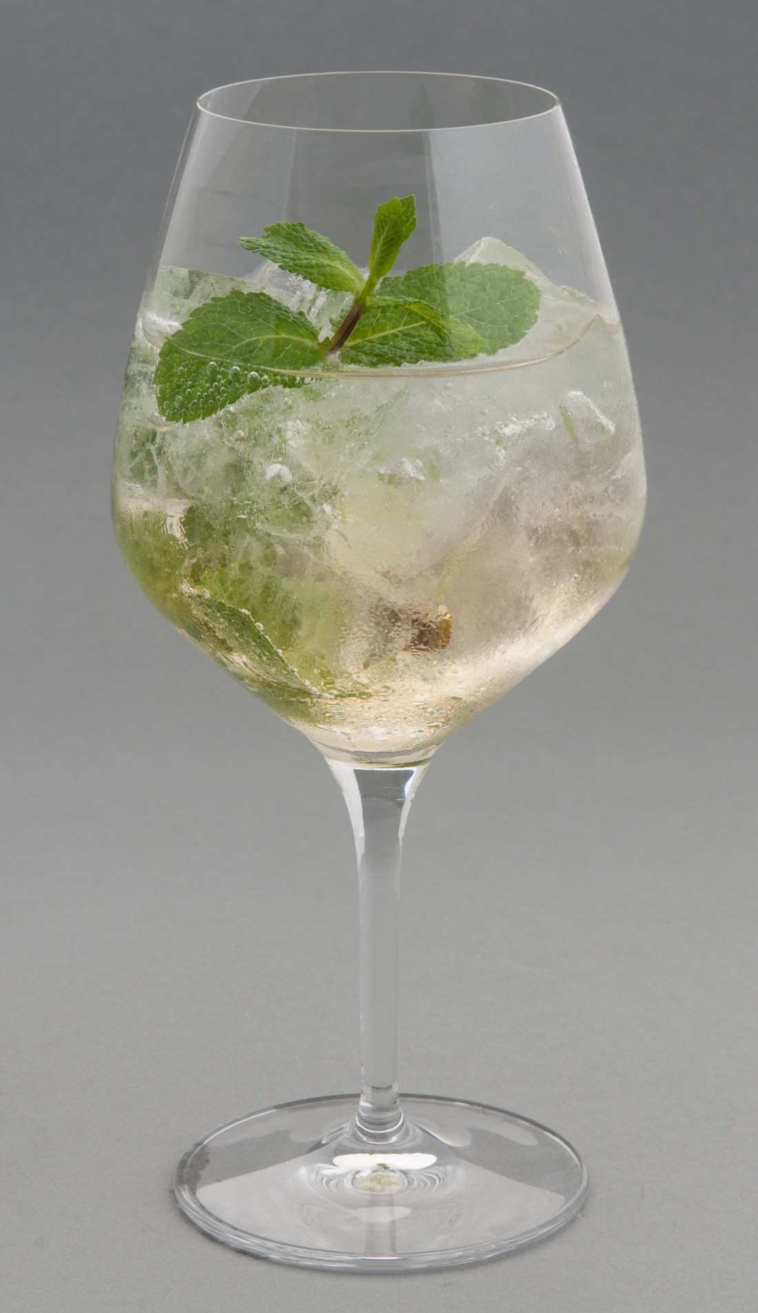 A tall mixed drink with mint in a glass